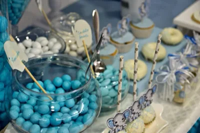 Confettata per battesimo nei toni dell'azzurro con vasi di confetti, dolcetti glassati, cupcake e piccole decorazioni coordinate sul tavolo. L'inquadratura ravvicinata mette in evidenza il tema cromatico uniforme e i dettagli pensati per la festa.