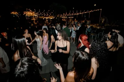Pista da ballo all'aperto con ospiti che danzano di notte sotto una fila di luci sospese nel giardino. Sullo sfondo si intravedono tavoli apparecchiati, sedute bianche e un allestimento elegante da evento privato.