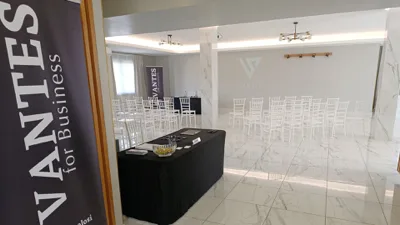 Sala per eventi aziendali con sedie disposte in file, tavolo relatori e banner VANTES visibili all'ingresso e sullo sfondo. L'ambiente è minimale, luminoso e adatto a presentazioni o meeting.