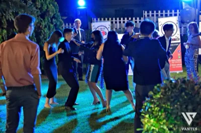 Gruppo di ospiti che balla sul prato durante una festa serale all'aperto, illuminata da luci blu e dalla postazione musicale sullo sfondo. La scena trasmette energia e atmosfera informale nel giardino della location.