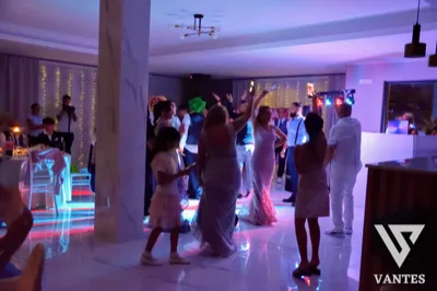 Serata di ballo in sala con invitati in pista, luci colorate e postazione DJ sullo sfondo. L'immagine trasmette un momento vivace di festa con atmosfera serale e intrattenimento musicale.