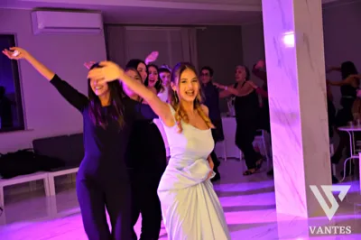 Serata danzante con una giovane festeggiata in primo piano e altri invitati che ballano dietro di lei sotto luci viola e rosa. La scena trasmette energia e atmosfera da festa per un diciottesimo compleanno.