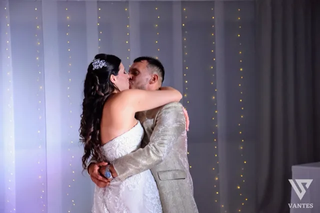 Gli sposi si abbracciano durante il ricevimento davanti a un fondale con piccole luci decorative. L'immagine restituisce un momento intimo e romantico della festa di matrimonio.