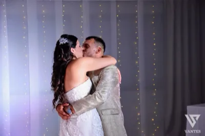 Gli sposi si abbracciano durante il ricevimento davanti a un fondale con piccole luci decorative. L'immagine restituisce un momento intimo e romantico della festa di matrimonio.