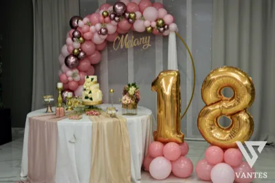Tavolo torta per i 18 anni di Melany con arco di palloncini rosa, numeri 18 dorati e torta decorata al centro. L'allestimento è elegante e scenografico, pensato come fondale principale della festa.